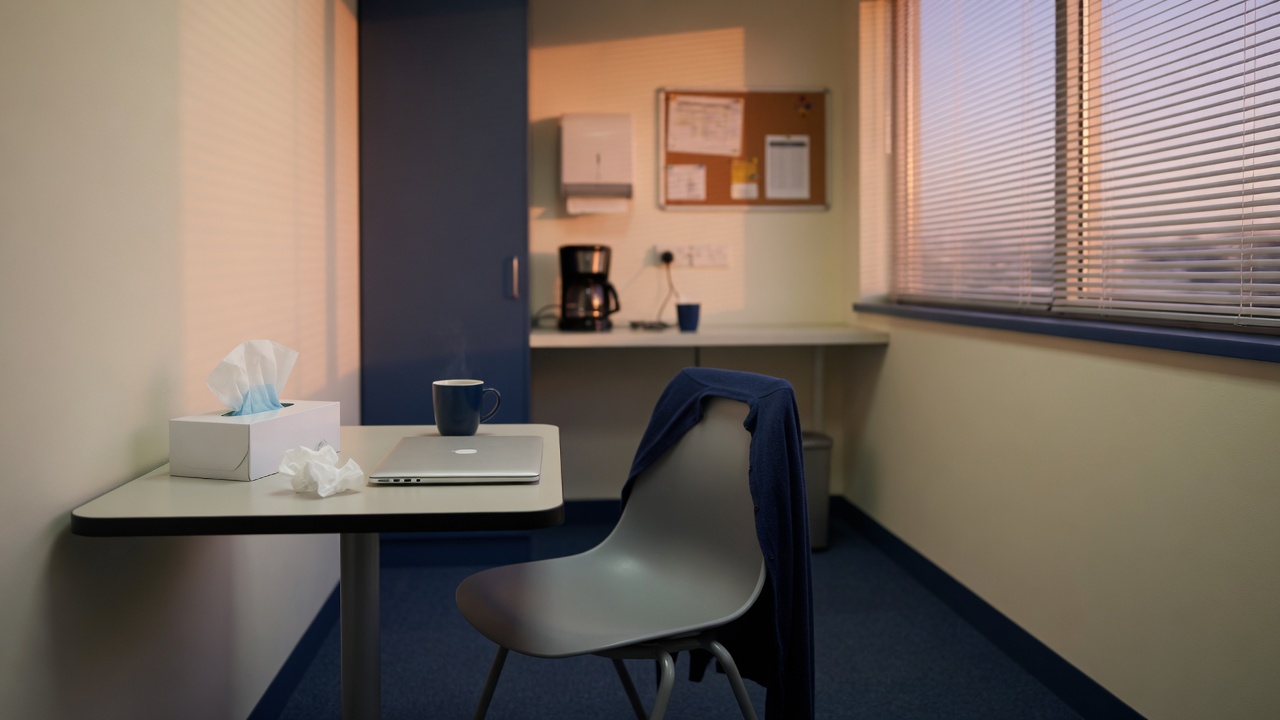 Quiet office break room with an empty chair and soft evening light — when grief walks into the workplace