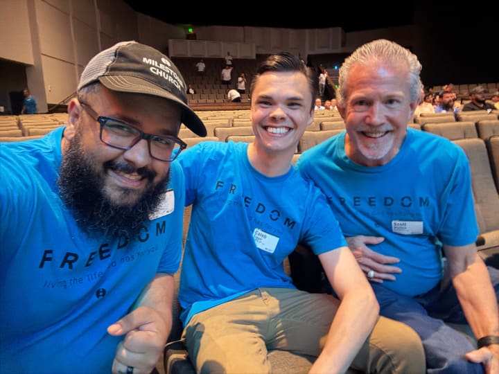 Three men at a Freedom men's conference wearing matching blue shirts