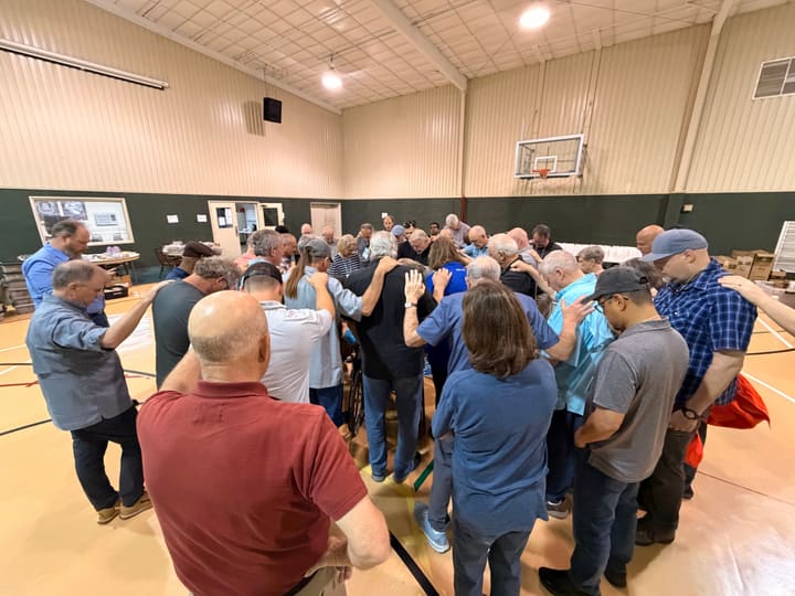 Group prayer with hands on shoulders inside a facility gymnasium