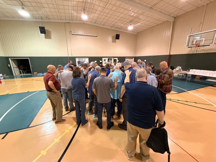 Men standing in a prayer circle inside a North Texas correctional facility gymnasium